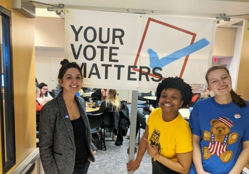 Political science professor with students in front of a Your Vote Matters sign